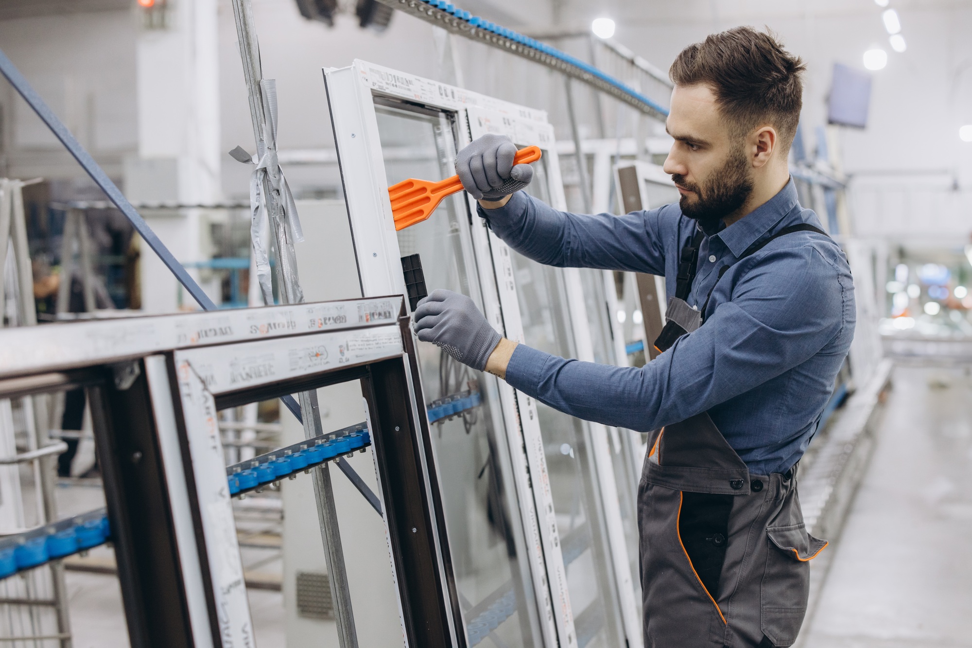 Factory worker assembling aluminum and pvc window frame